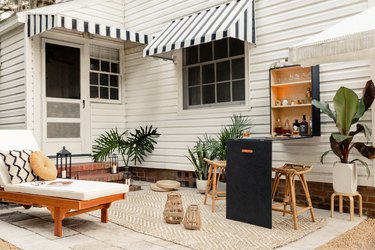 Patio with a black plywood bar table-cabinet set, tropical plants, lanterns, rattan furniture, and black-white accents