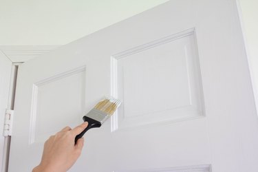 Hand painting white door with paint brush