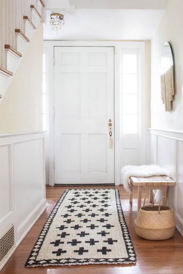 Hallway Runner Ideas in White hallway with geometric black-white jute rug on wood floor with basket