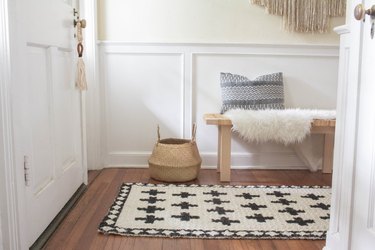White and black geometric jute rug with basket, bench with pillow and fur rug