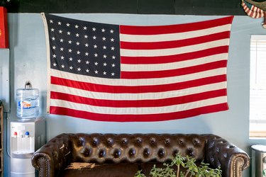 Brown leather sofa with American flag on gray wall and water cooler