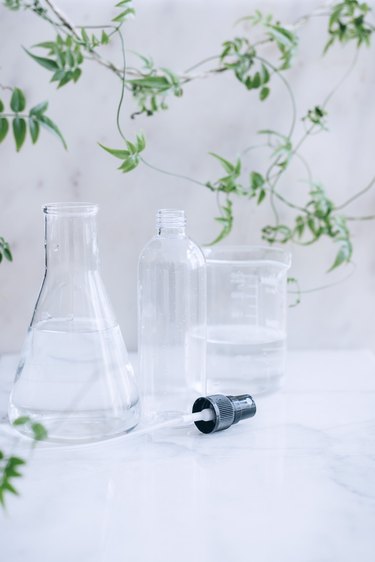 measuring cups and a spray bottle filled with water and rubbing alcohol