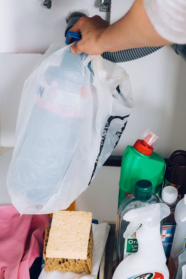Hand holding plastic bag with cleaning containers