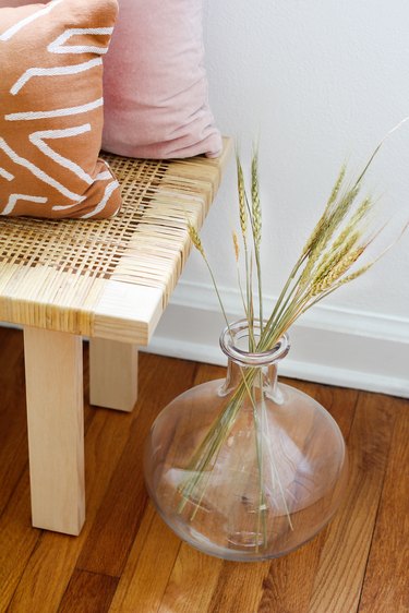a globe-shaped glass vase full of dried grasses