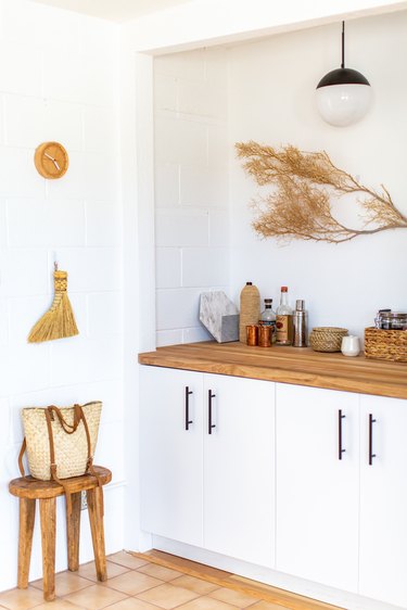 a decorative dried branch mounted on a wall above an appliance-filled wooden counter