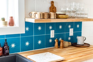 a kitchen wall with floating shelves that match the wooden countertop