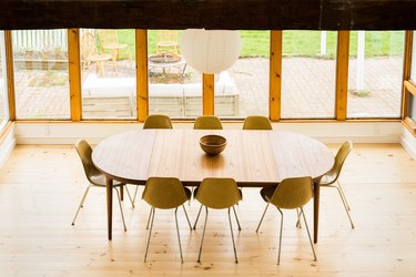 a oval dining table surrounded by mid-century molded plastic chairs