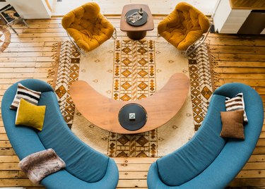 blue curved couches with a curved coffee table on a floor with rustic planks and a southwestern-patterned rug