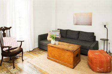 an l-shaped sectional couch with a distressed wooden chest for a coffee table in a room with rough plank floors