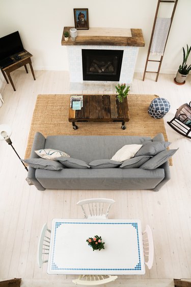 a gray couch, rustic wood coffee table on casters, and a country dining table that is white with blue trim