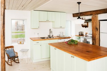 2021 kitchen color trend with a wooden ceiling, a pine-topped island, wood floors, green cabinets, and a wooden ceiling