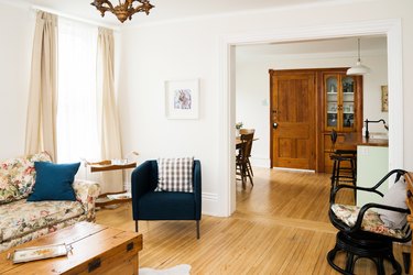 a large sitting room with clean white walls and a floor made of narrow wooden strips