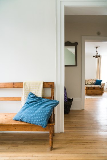 a wooden bench with a pillow on it in the foreground; in the background a matching wooden chest can be seen