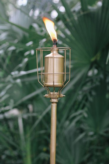 an industrial diy outdoor torch with a gold metallic finish and a lit flame