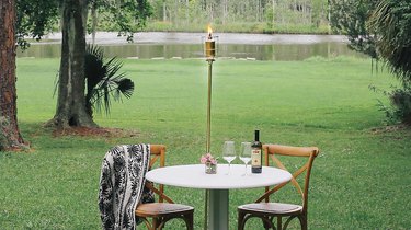 an industrial diy torch next to an outdoor dining table set with wine glasses