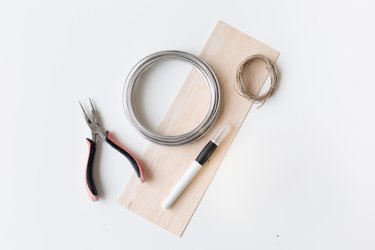 Wire cutter, wire, thread, pen, and tissue paper against a white background