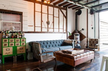 a eclectic room with a blue couch, green bar, exposed beams, and a wood-burning stove