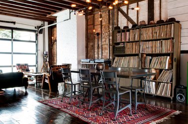 a distressed metal dining table and chairs in front of a five-level shelving unit stocked with vinyl records