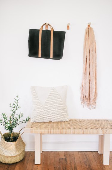 Hallway Furniture Ideas withthree coat hooks made from thick wooden dowels and a leather loop hanging below, with clothes and bags hanging from them