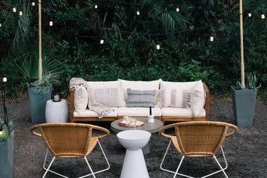 Round wicker chairs, white cushioned sofa, white stool and string lights