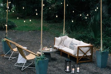 Patio furniture surrounded by string lights supported by wood poles