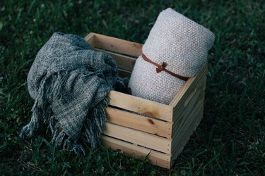 Outdoor storage and organization idea with a wood plywood crate with a gray blanket and a white blanket