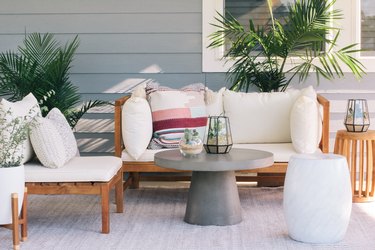 Round gray table with succulent terrariums and white cushioned deck furniture