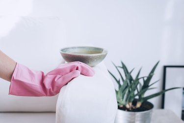 Pink cleaning gloves cleaning stain on white couch