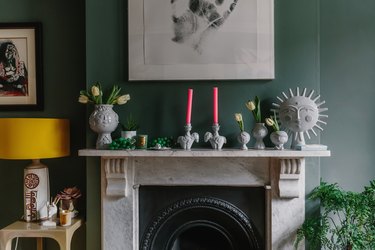 green walls in living room with marble vintage fireplace and hot pink candlesticks