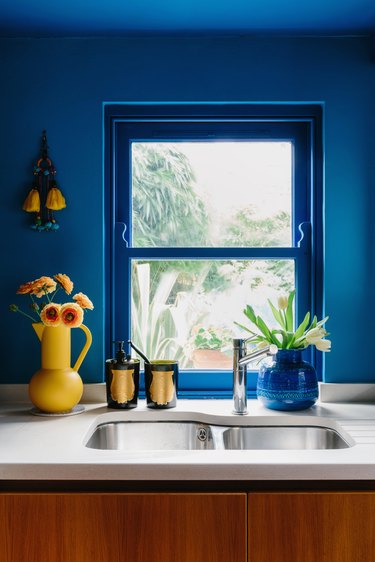 blue walls in kitchen with fresh yellow flowers next to the sink