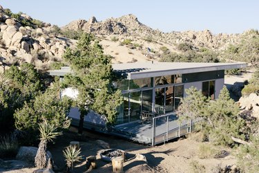 a pre-fab home with a glass and corrugated metal exterior and a large porch