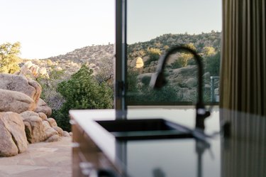 desert hills seen through large living room windows; a bar sink is in the foreground