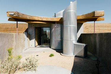 the back door of a futuristic house flanked by two vertical corrugated metal pipes