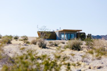 the exterior of a small desert house whose roof is curved like the hull of a ship