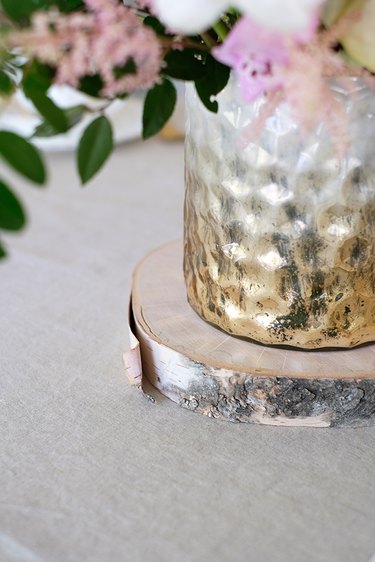 Gold-white textured vase on wood coaster on table