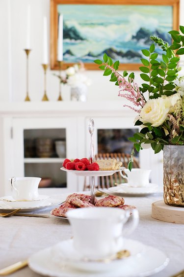 Vase of flowers with white china on dining table