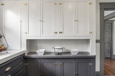 white and gray kitchen with two tone cabinets and brass knobs