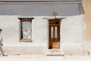 White 1890's Adobe Row House, with a wood front door.