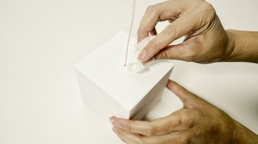 wiping excess glue away from the top of a wooden block into which a wire has been inserted