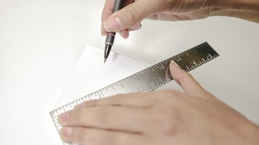 using a rule and a pen to mark the center of a wooden block