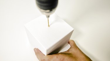 using  power drill to drill a hole in the center of a wooden block