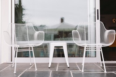 Two plastic modernist style chairs with a small white metal stool in between.