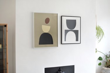 Two framed DIY graphic art pieces on white wall in room with plants and wood-framed glass cabinet