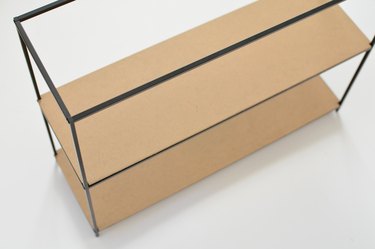 Top-down view of black metal-framed shelf unit with two brown cardboard shelves against a white background