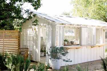 A white garden shed with open windows and shelf-like window sills