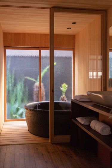 a large soaking tub in a minimalist wood-paneled bathroom