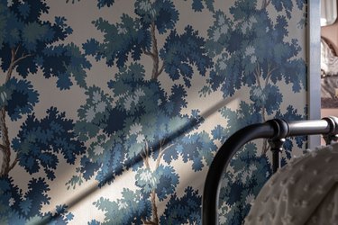 Vintage blue tree wallpaper next to the top of a black bar headboard.