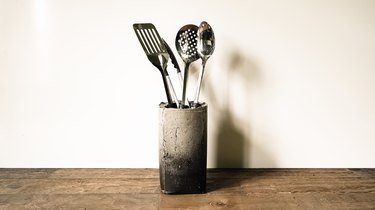 Concrete vase with utensils on wood countertop