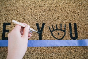 touching up the paint on a nearly finished painted doormat