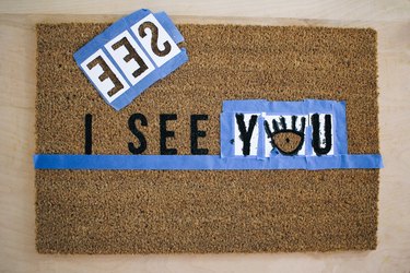 a brown doormat with a horizontal tape guideline and templates for one word taped in place